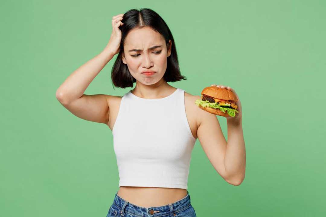 A woman holding a hamburger in her hand.