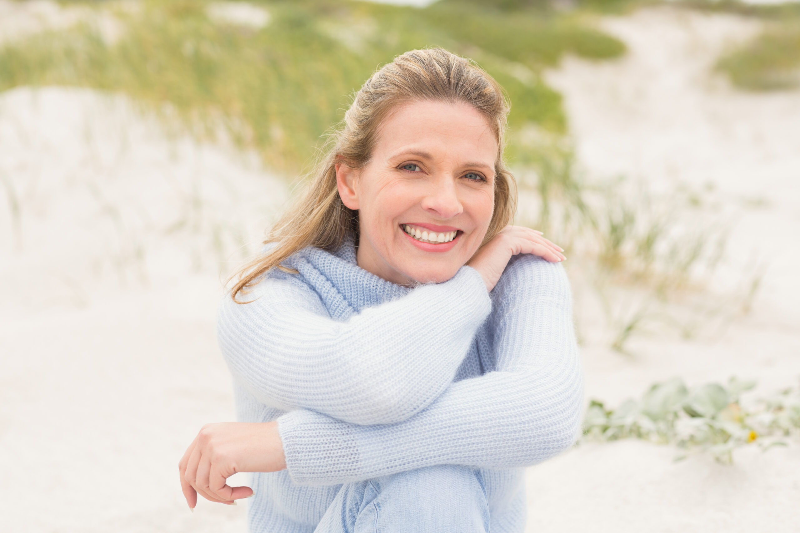 Smiling Woman Sitting On The Sand At The Beach